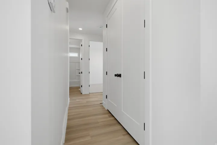 Light wood-finish flooring, white walls, and white interior doors with matte black hardware