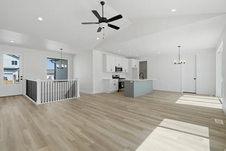 Open-concept living area with wood-finish flooring, vaulted ceiling, and recessed lighting