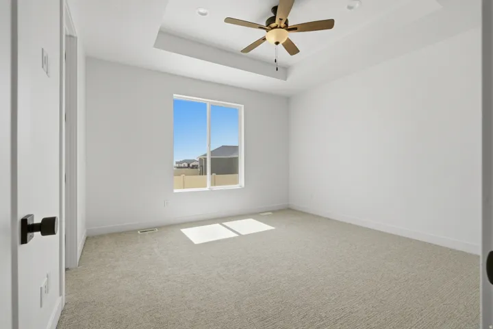 Recessed lighting, ceiling fan, tray ceiling detail, large window, and light-toned carpet
