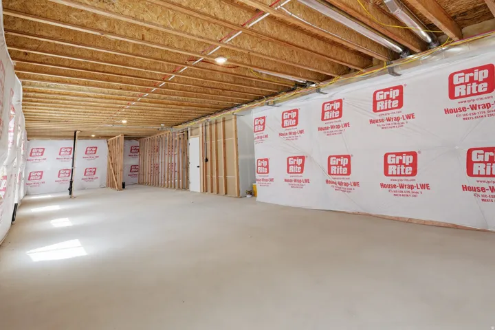 Unfinished basement with exposed ceiling joists, concrete flooring, and partial wall framing