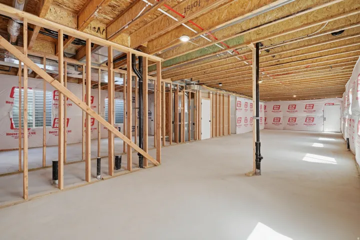 Unfinished lower level with wood framing, exposed ceiling joists, and concrete flooring