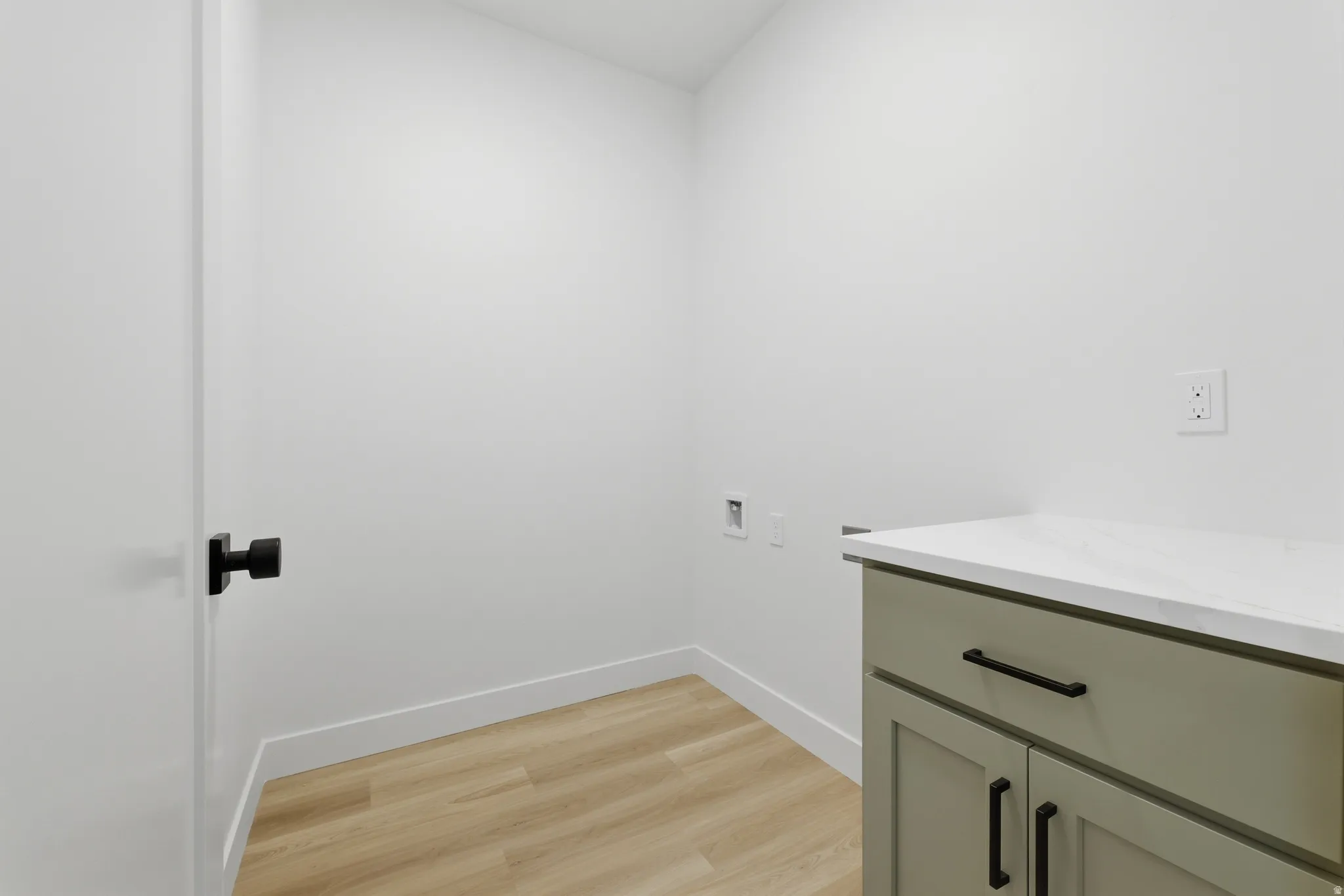 Modern cabinetry with matte black hardware, white countertop, and wood-finish flooring