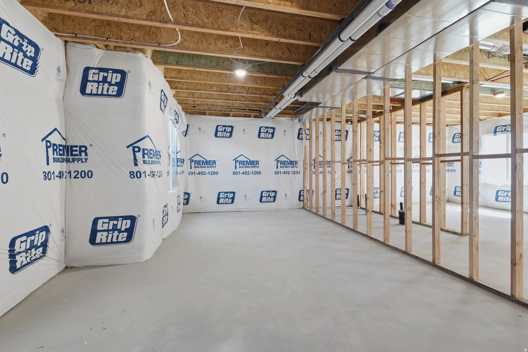 Unfinished basement space featuring exposed wood framing, concrete flooring, and ceiling-mounted utilities