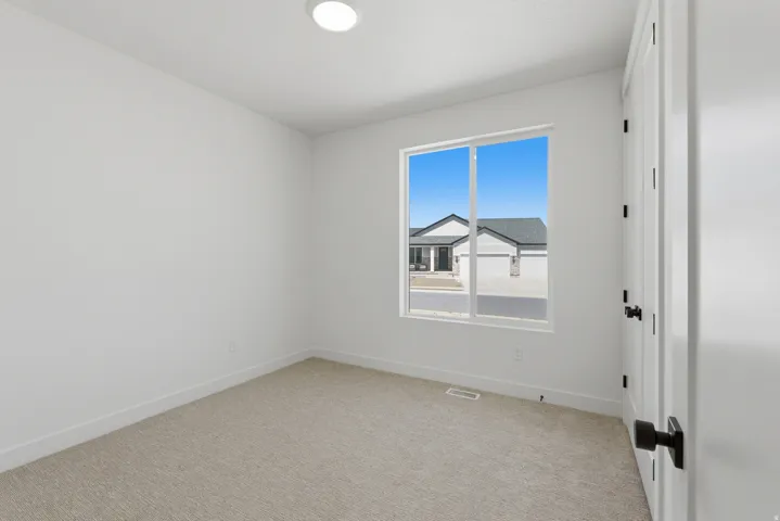 Neutral-toned carpet flooring, white walls, and a large window providing natural light