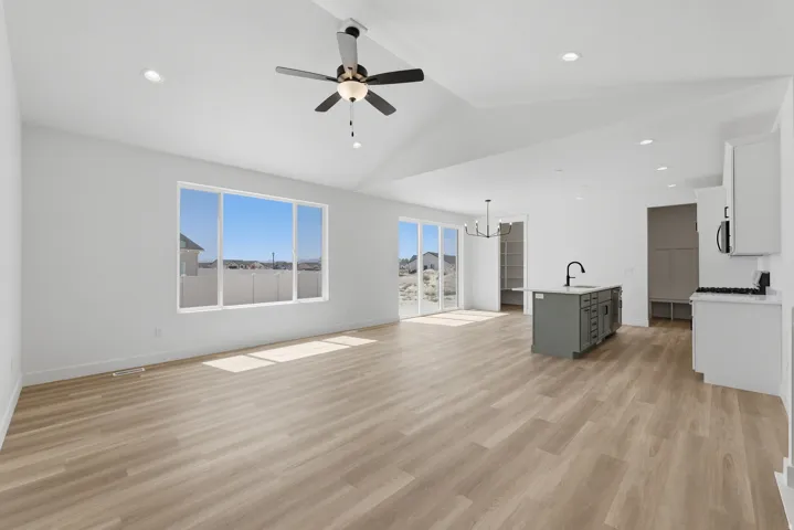 Spacious open-concept layout with wood-finish flooring, vaulted ceilings, and recessed lighting