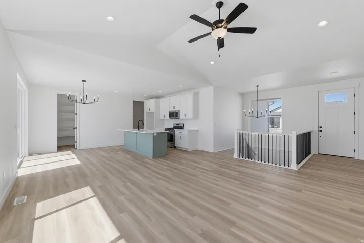 Open-concept living space with wood-finish flooring, recessed lighting, and a vaulted ceiling with a ceiling fan