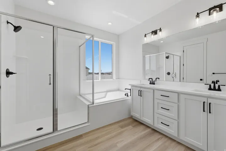Dual vanity with white shaker-style cabinetry, matte black hardware, and integrated sinks