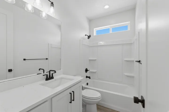 White vanity with white countertop, undermount sink, and black faucet