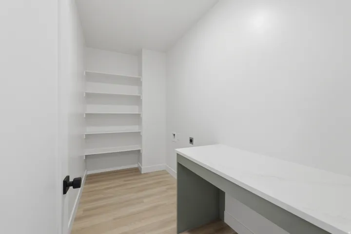 Built-in shelving, wood-finish flooring, white walls, built-in countertop, matte black door hardware