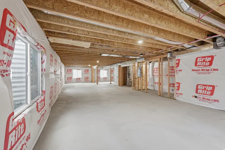Open framed basement with multiple egress windows and exposed wood ceiling joists