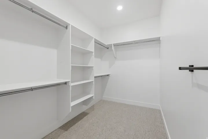 Walk-in closet featuring built-in shelving, multiple hanging rods, recessed lighting, and carpet flooring