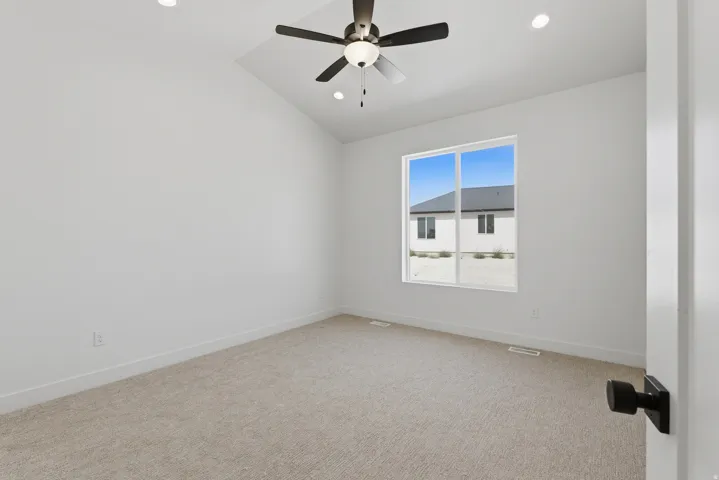 Vaulted ceiling with a ceiling fan, recessed lighting, expansive window, carpeted flooring, and a white interior door with matte black hardware