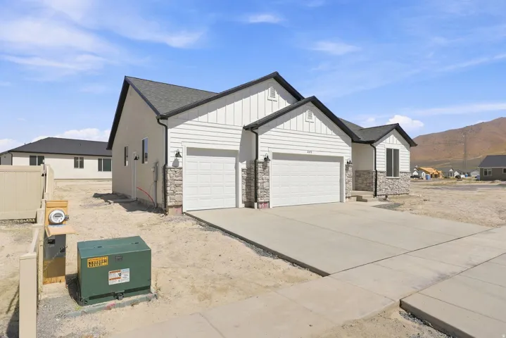 Exterior featuring horizontal siding with board and batten accents, stone veneer detailing, and a two-car garage