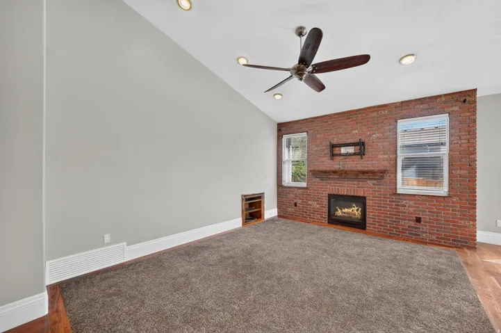 Exposed brick accent wall with a gas fireplace and a wood mantel