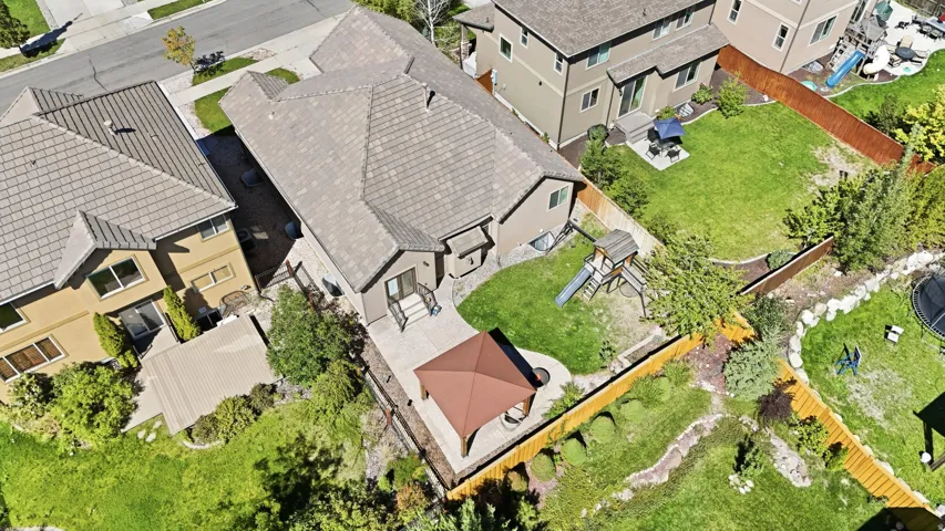 Expansive backyard featuring a manicured lawn, established landscaping, a multi-level patio, and a covered pergola