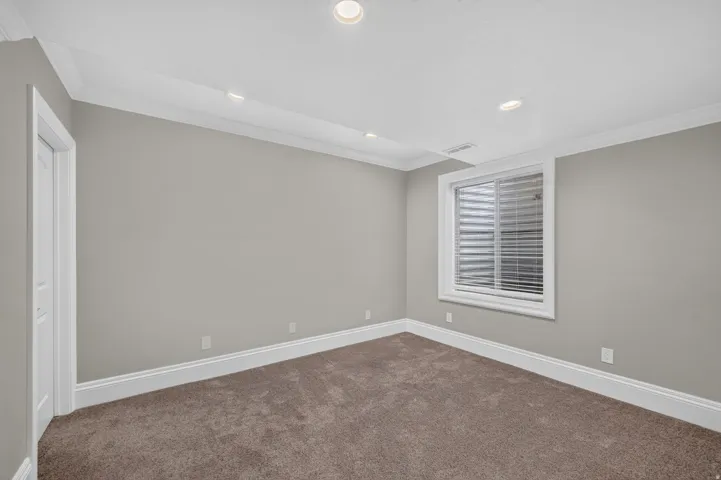 Recessed ceiling lighting, crown molding, light gray wall finish, white trim, and brown carpet flooring