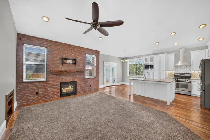 Exposed brick wall with fireplace, wood mantel, and two windows