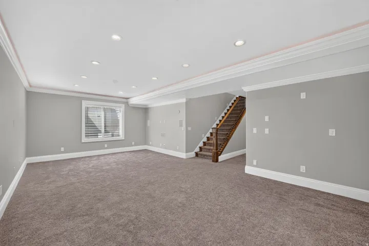 Recessed lighting illuminates the carpeted living area with crown molding accents