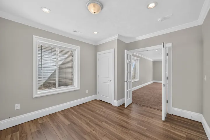 Wood-finish flooring, recessed lighting, crown molding, double French doors, and a paneled door