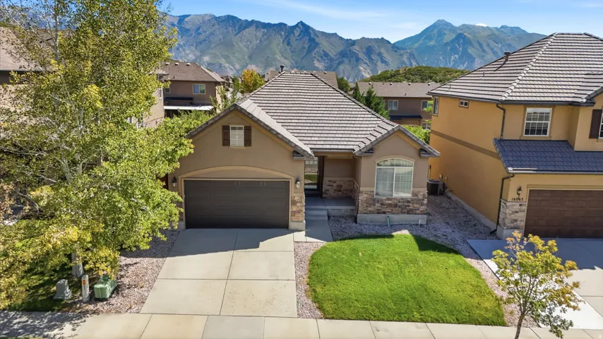 Stucco exterior with stone accents, a tile roof, and an attached two-car garage