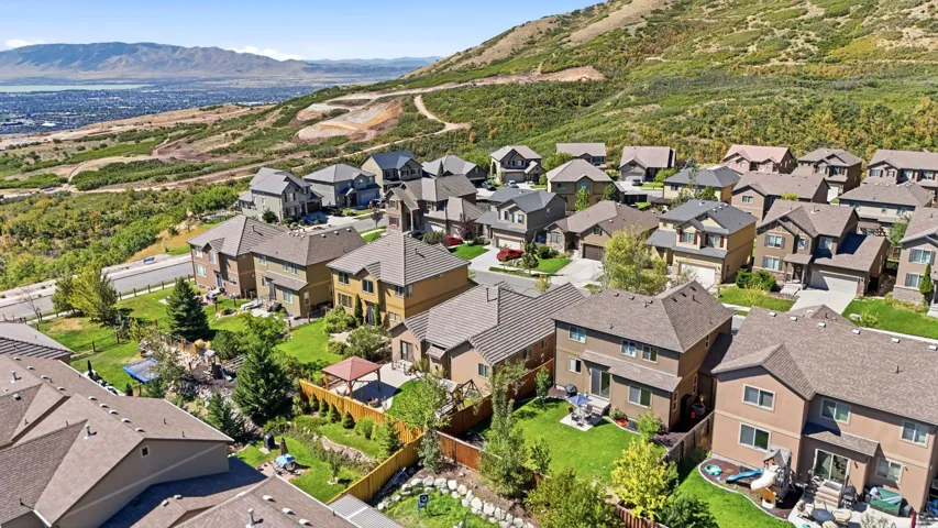 Residential community with varied architectural styles, individual fenced yards, and mountainous terrain