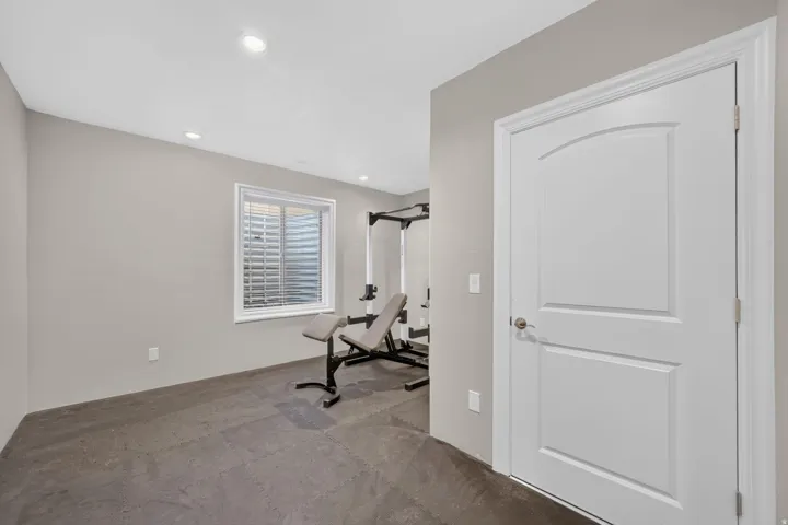 Recessed lighting, light gray wall finish, white interior door with arched paneling, and a white-framed window