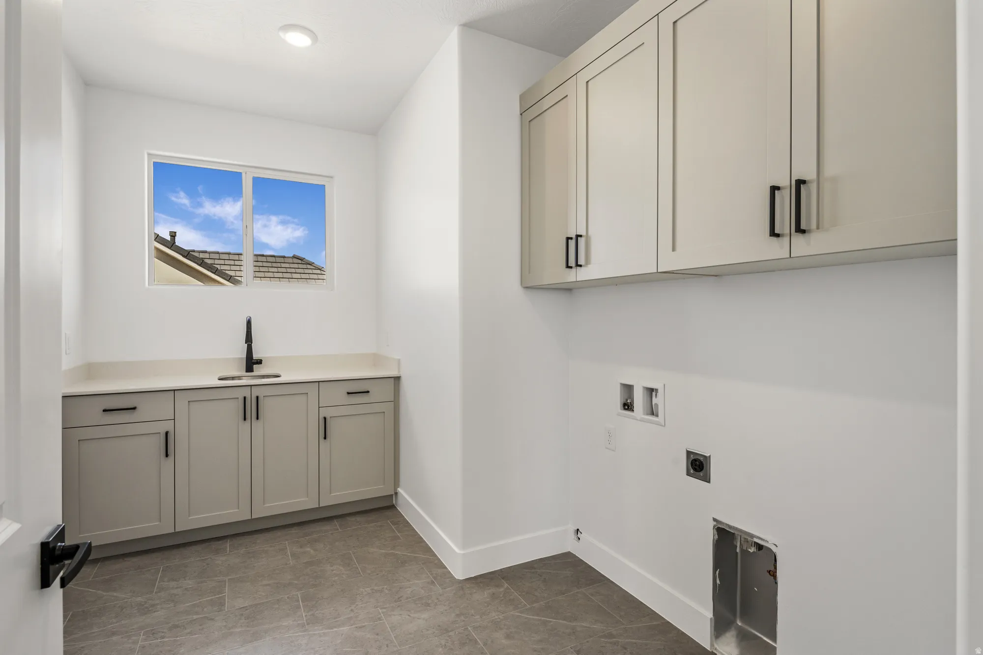 Laundry room featuring grey-finish cabinetry, light-toned countertop, and a black faucet