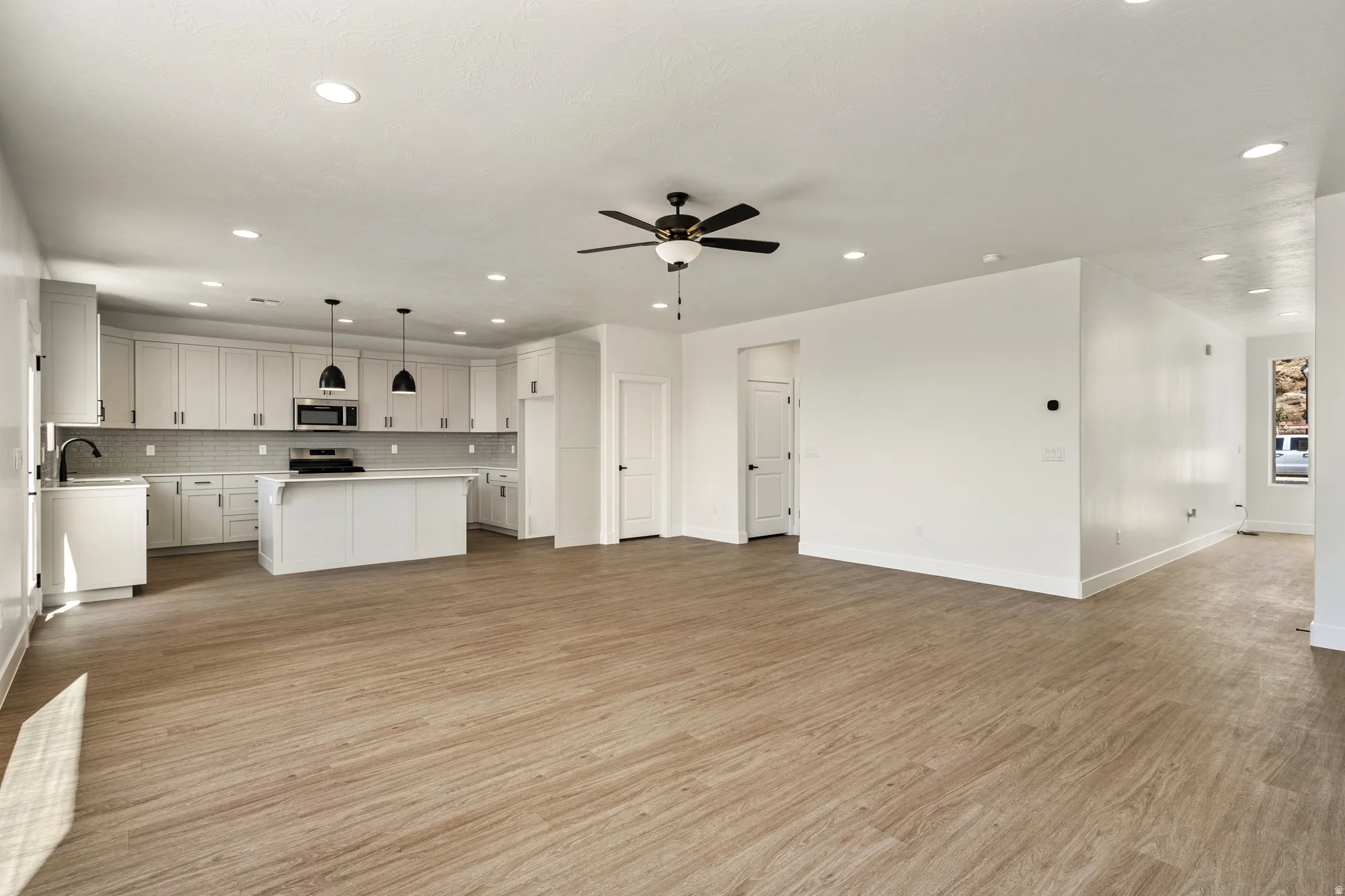 Open-concept living space featuring wood-finish flooring, recessed lighting, and a modern ceiling fan