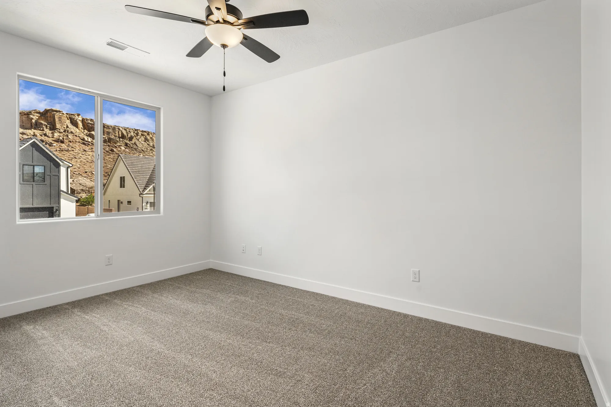 Expansive window with mountain scenery, plush carpet flooring, recessed lighting, and a ceiling fan with integrated light