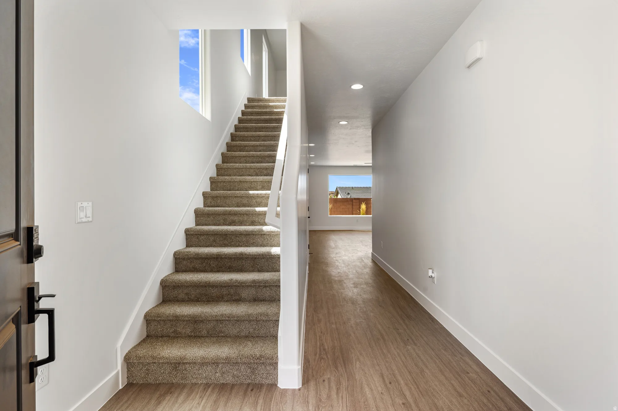 Entryway featuring wood-finish flooring, recessed lighting, a carpeted staircase, and an upper window