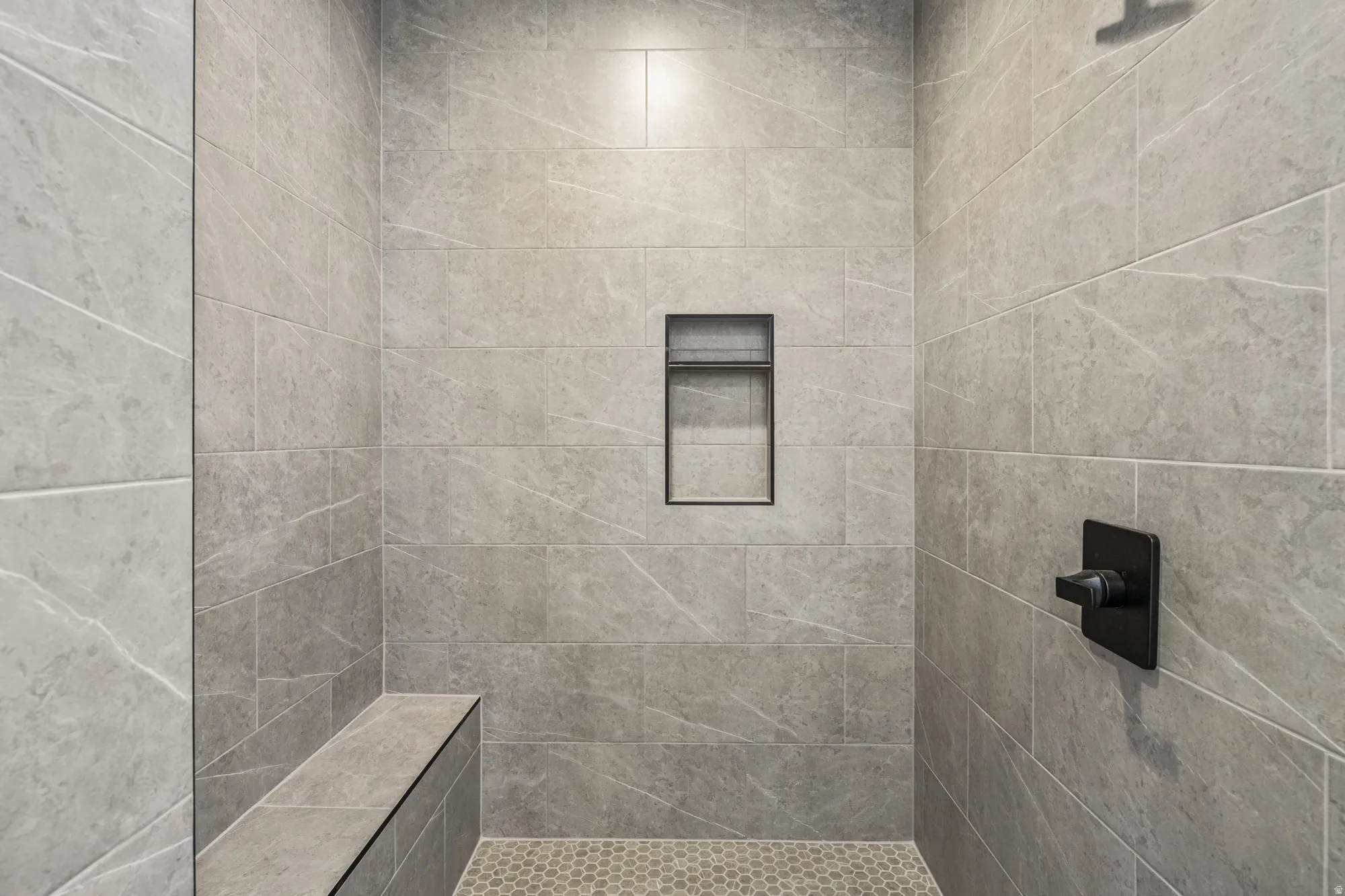 Walk-in shower with large format tile, integrated bench, and matte black fixtures