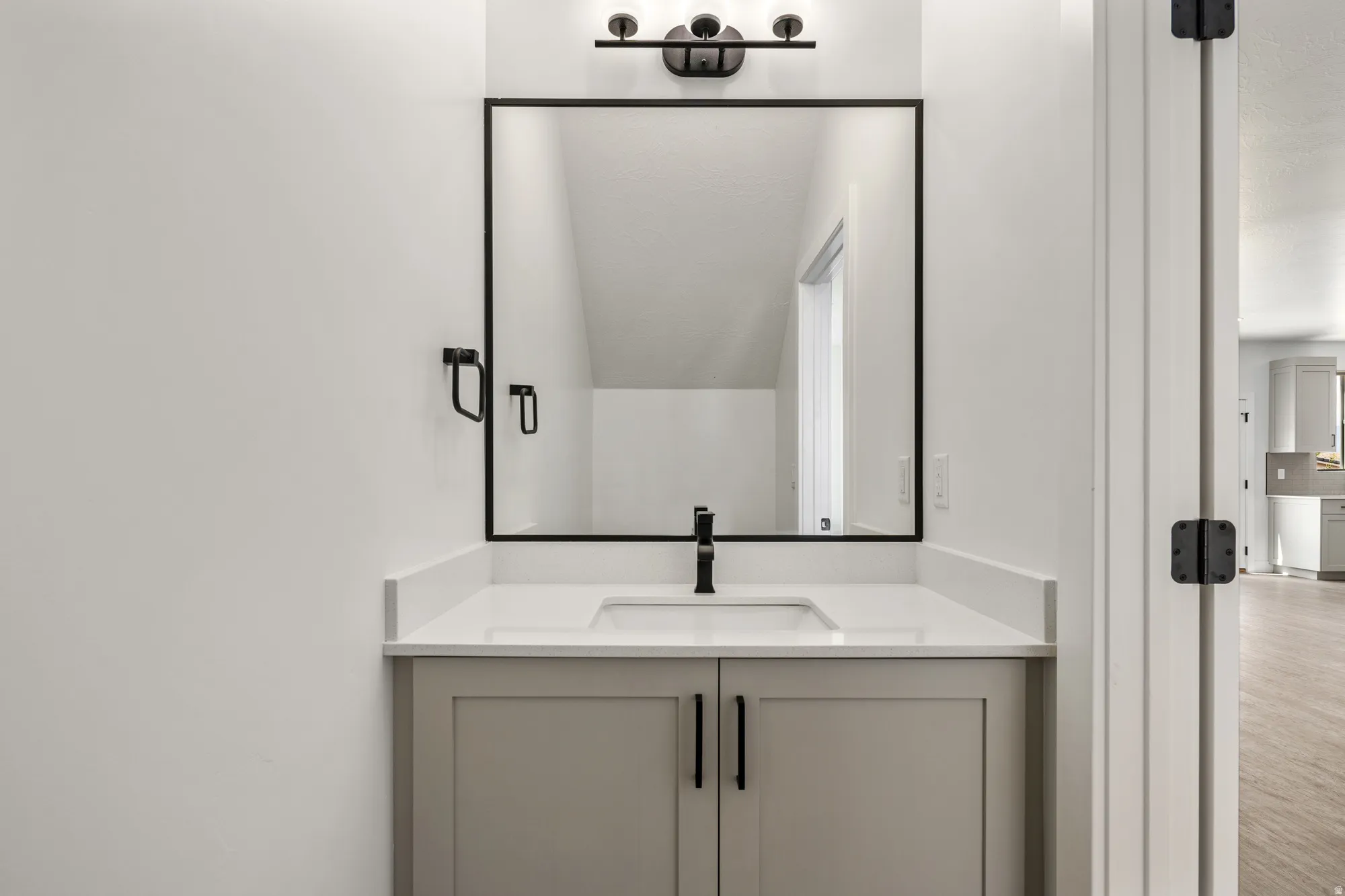 Modern bathroom vanity featuring dual matte black hardware pulls, a white quartz countertop, and an integrated rectangular sink