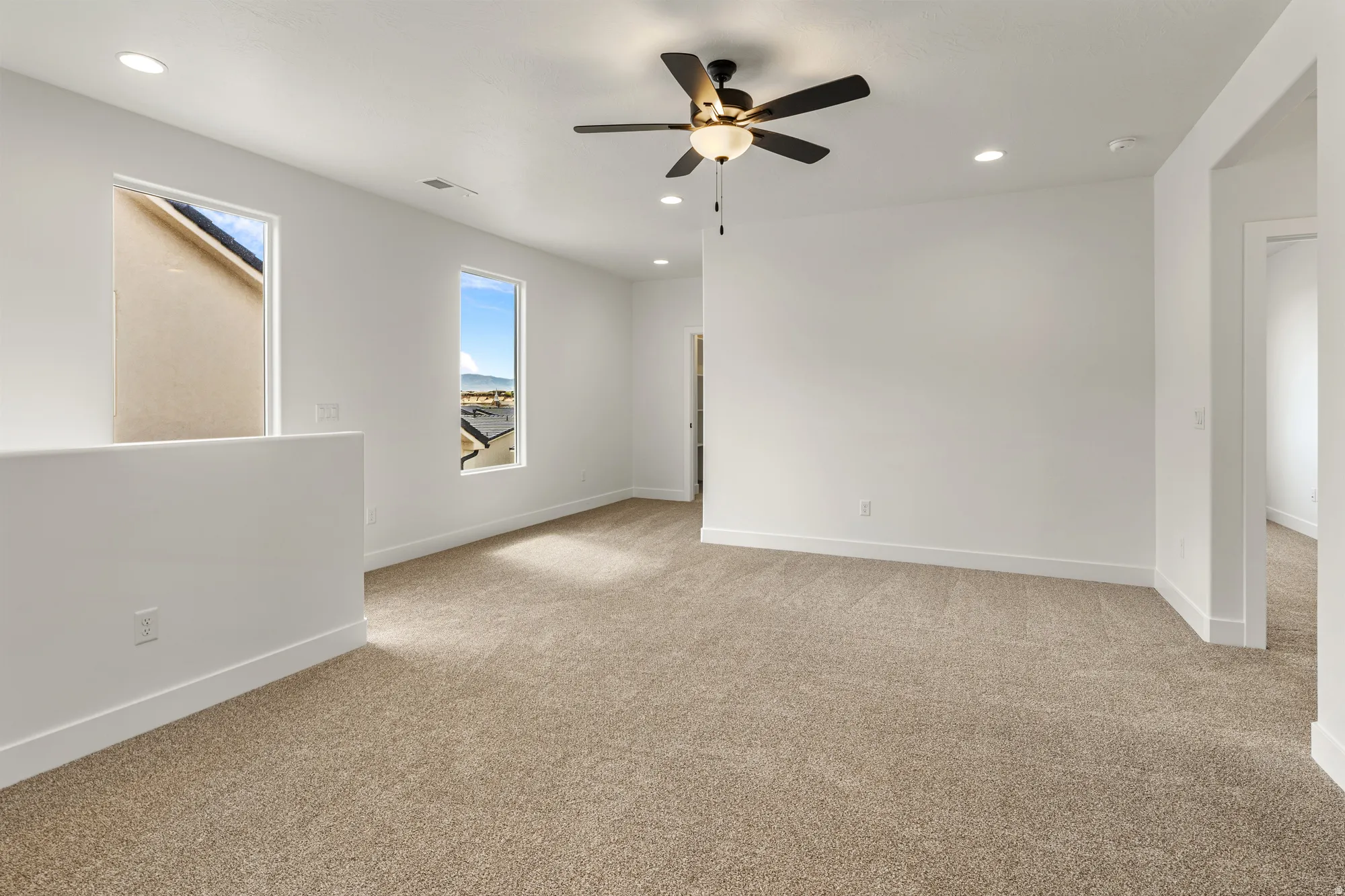 Carpeted room featuring a ceiling fan with integrated lighting, recessed lighting, and two windows