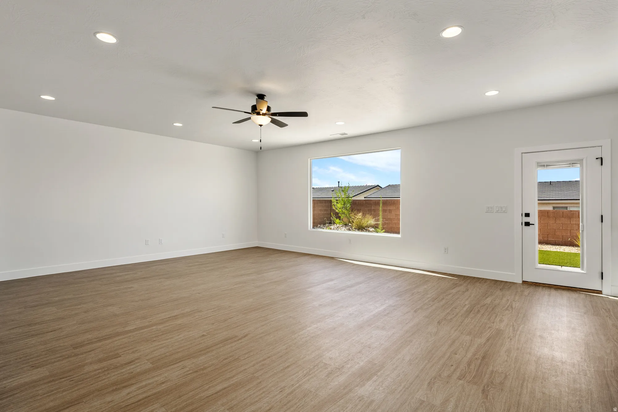Spacious room featuring wood-finish flooring, recessed lighting, and a ceiling fan