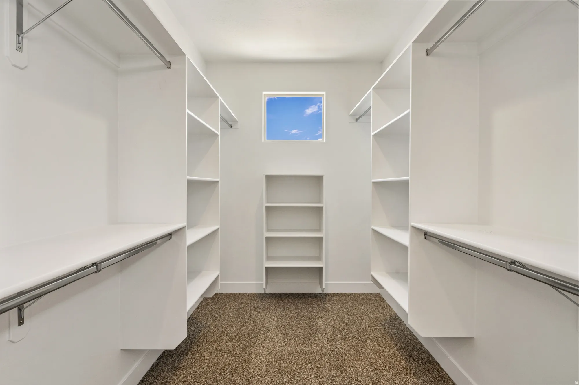 Walk-in closet with built-in shelving, hanging rods, and a square window