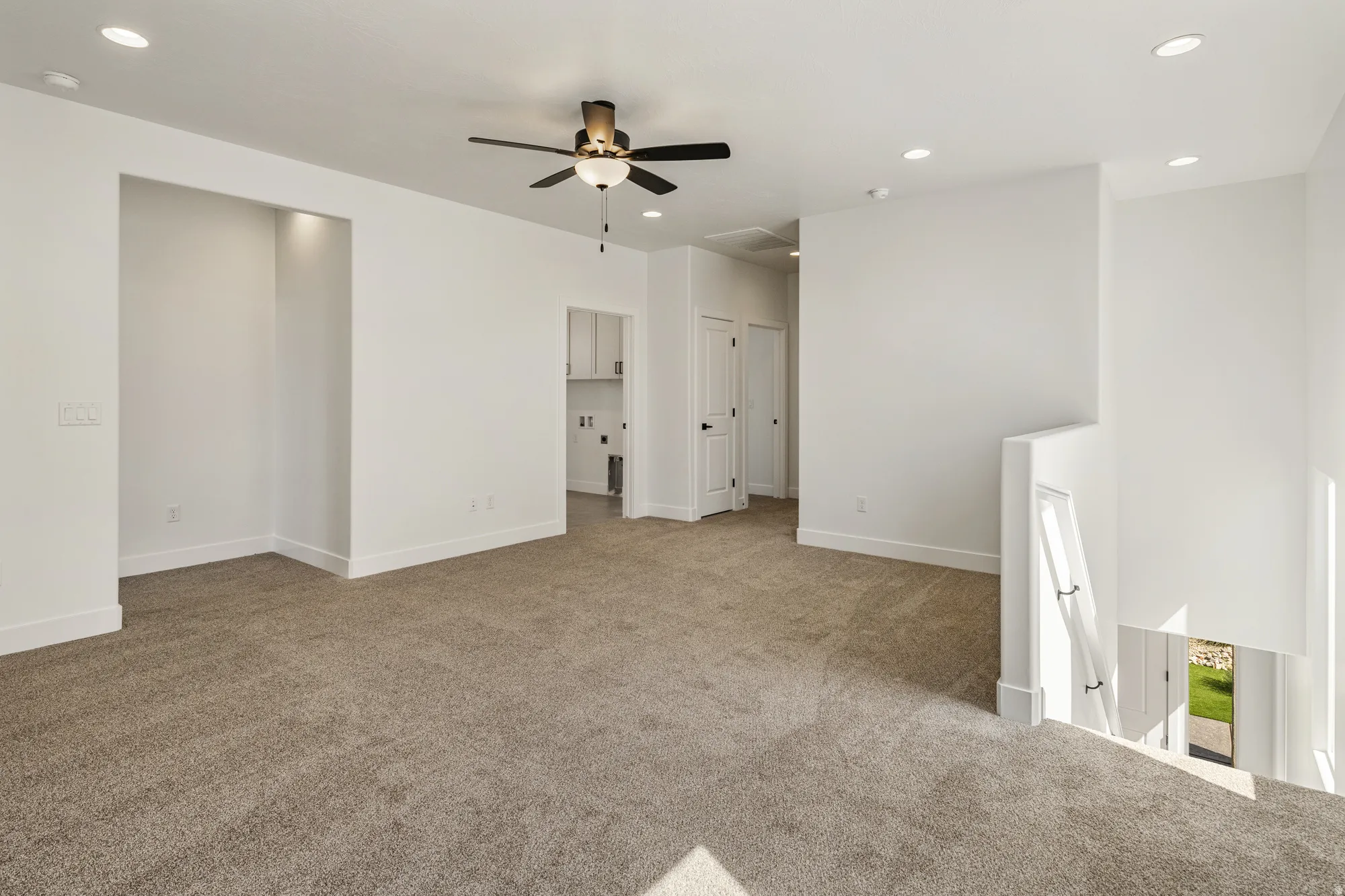 Expansive carpeted space featuring recessed lighting, a ceiling fan, and an architectural niche with accent lighting
