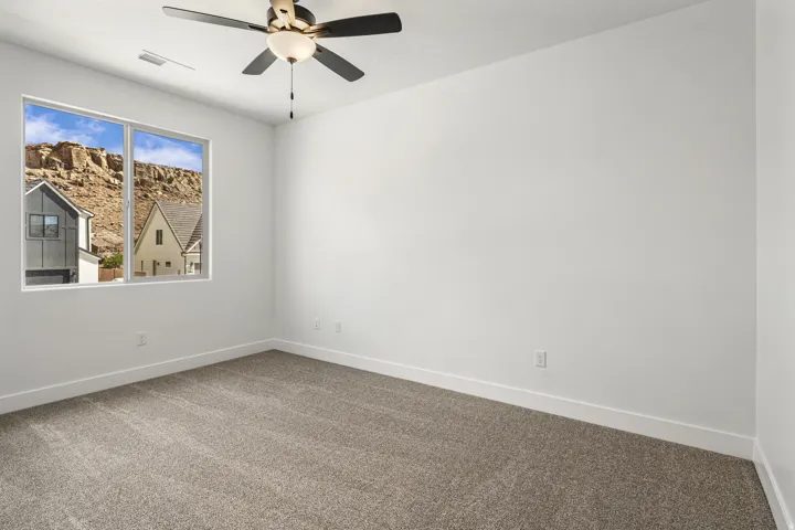 Expansive window with mountain scenery, plush carpet flooring, recessed lighting, and a ceiling fan with integrated light