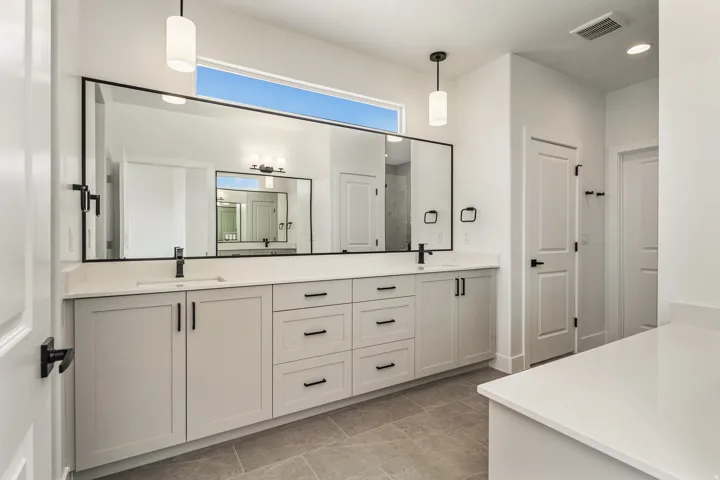 Dual vanity with white shaker cabinetry, matte black hardware, and an expansive integrated mirror