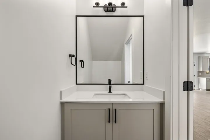 Modern bathroom vanity featuring dual matte black hardware pulls, a white quartz countertop, and an integrated rectangular sink