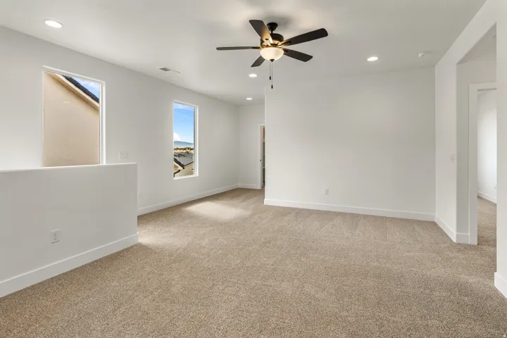 Carpeted room featuring a ceiling fan with integrated lighting, recessed lighting, and two windows