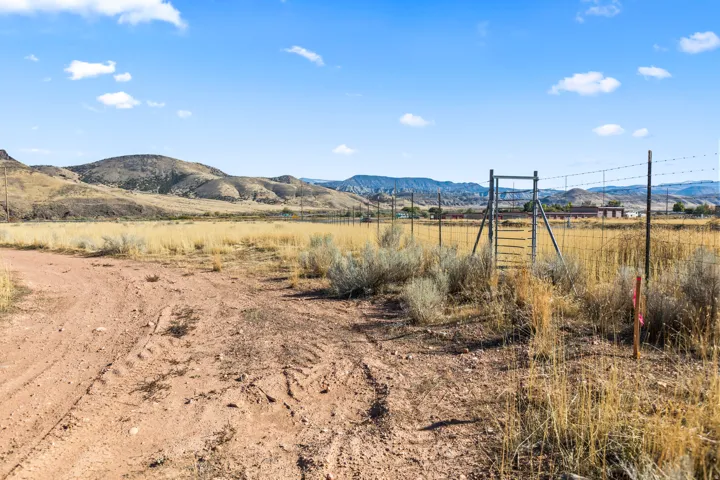 Expansive land parcel featuring a dirt road, natural vegetation, and distant mountains