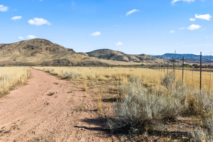 Expansive terrain featuring a dirt road, natural vegetation, and distant mountains