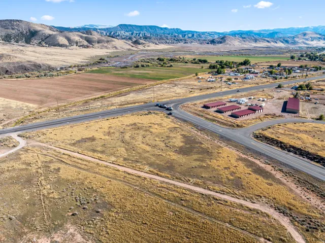 Expansive land parcel with highway frontage, surrounding natural topography, and distant mountain backdrop
