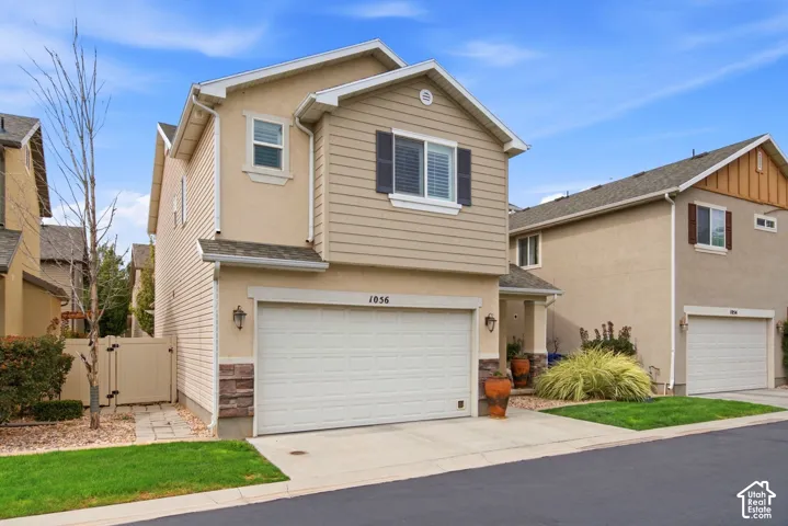 Two-story residence featuring a stucco and siding exterior, an integrated garage, and a gated side pathway