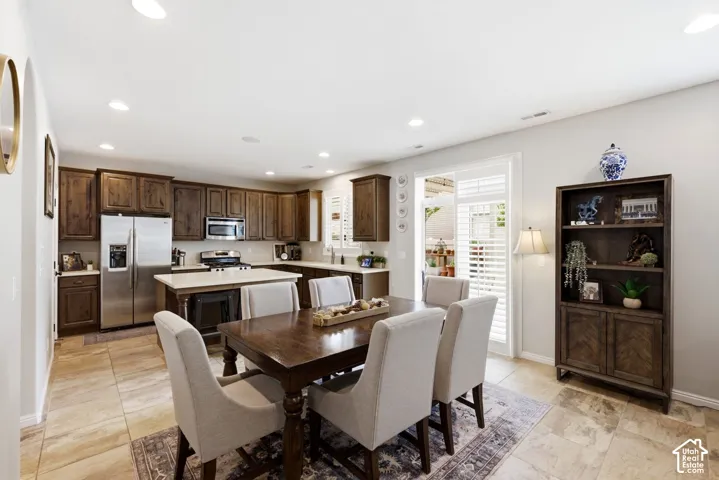 Kitchen and dining area featuring a center island, wood-finish cabinetry, stainless steel appliances, and tile flooring
