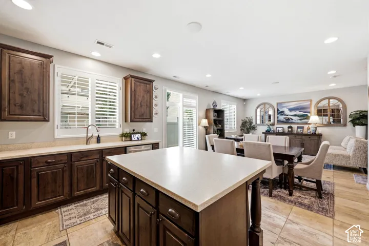 Kitchen featuring dark wood-finish cabinetry, light countertops, a center island, recessed lighting, and tile flooring