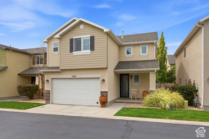 Two-story residence featuring a garage, covered entry, and mixed material exterior with siding and stucco finishes