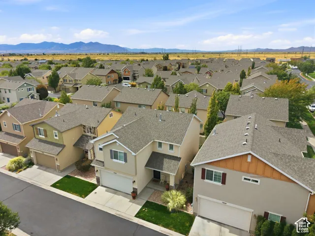 Residences featuring attached garages, paved driveways, and manicured landscaping