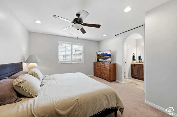 Recessed lighting, ceiling fan, arched doorway, window with plantation shutters, dual sink vanity with wood cabinetry