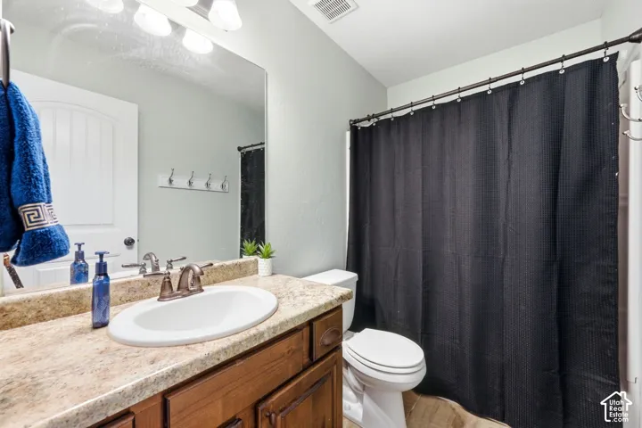 Bathroom featuring a wood-finish vanity, light-toned countertop, integrated sink, and an expansive mirror